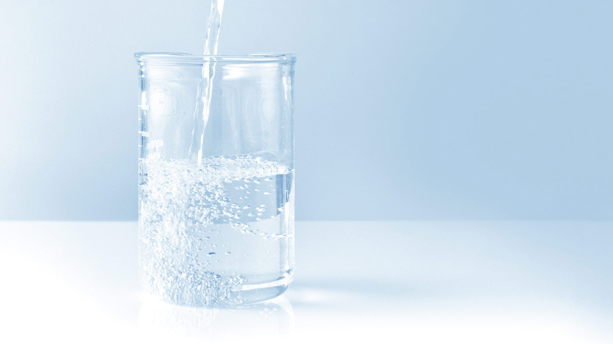 Water being poured into a glass against a light background